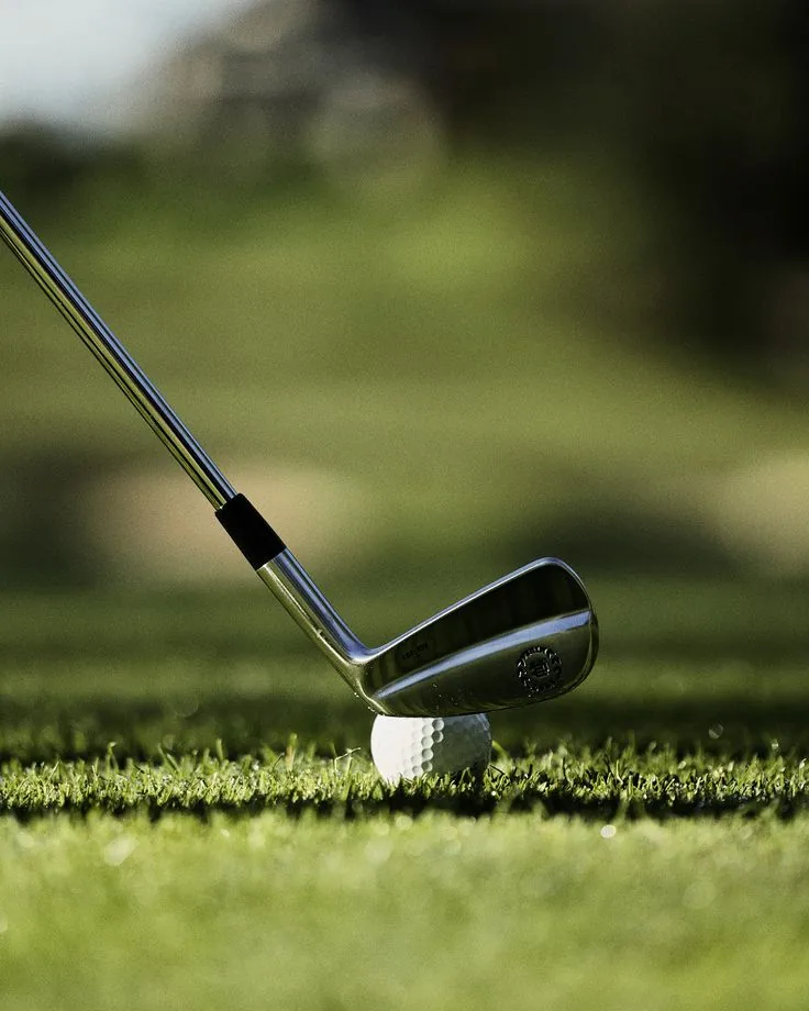 A golf club poised behind a ball on grass, representing Loft Golfing courses and guided play.